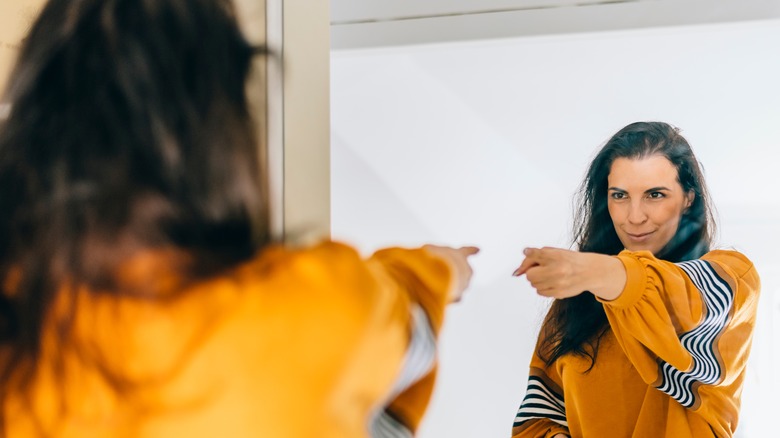 happy woman pointing at herself in a mirror