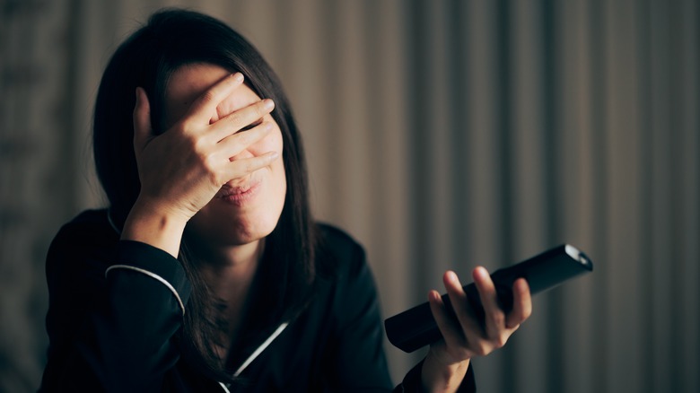 Woman covering eyes at TV