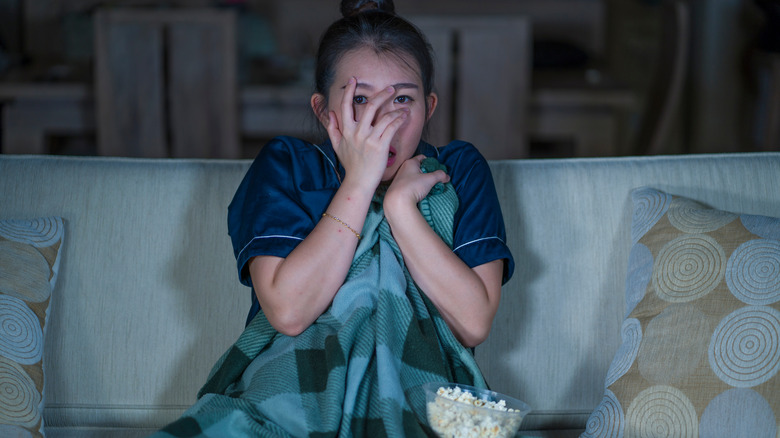 Woman covering her face as she watches a movie