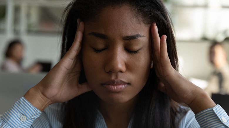 Woman pressing her fingers to her temples 