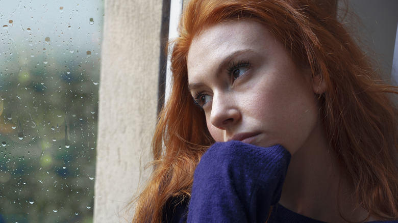 Woman sitting alone looking out of a window