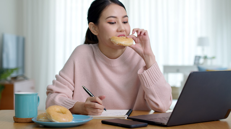 Woman eating donut while working