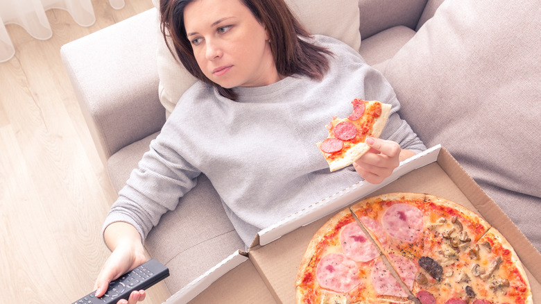 Woman lying on sofa with pizza