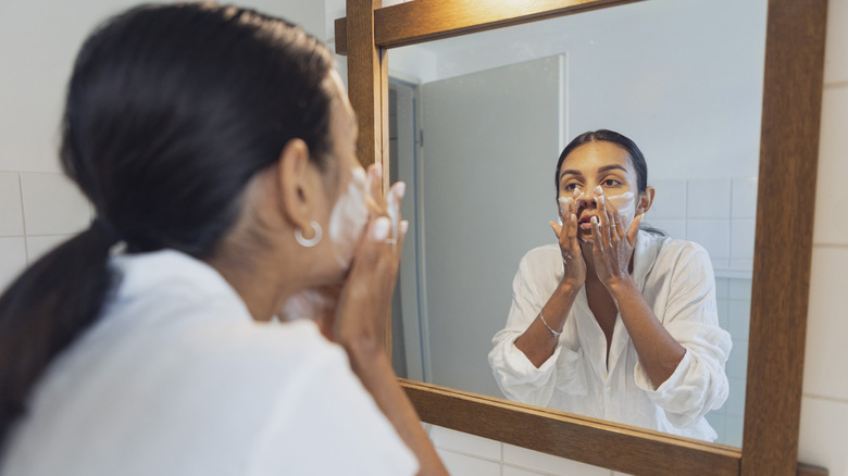 woman washing face in mirror