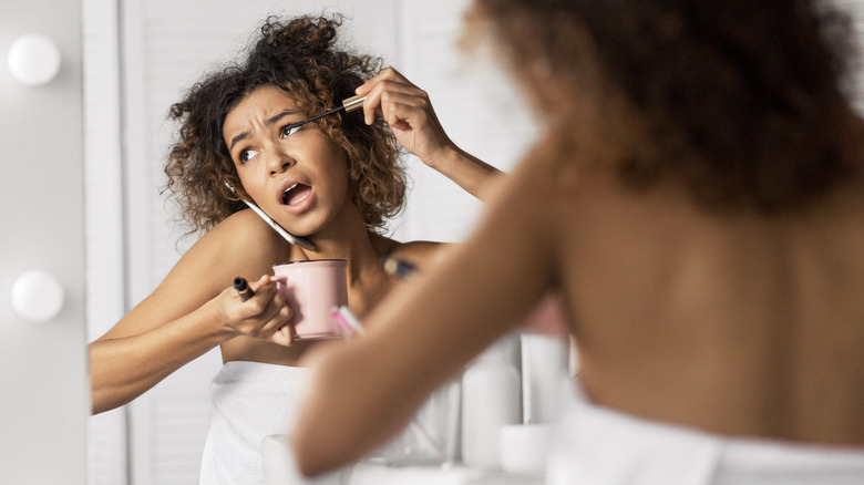 woman annoyed while putting on makeup