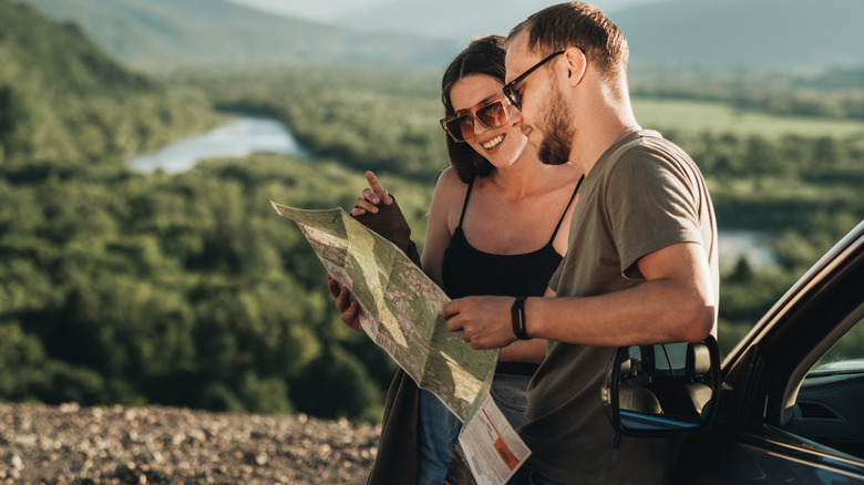 A couple on a road trip looking at a map