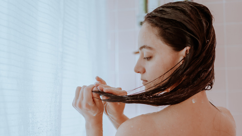 Woman looking at her hair in shower
