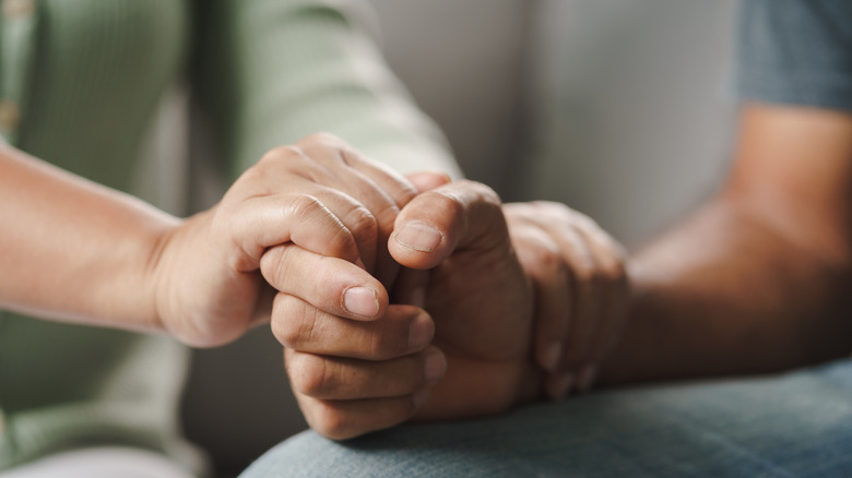 Close up of woman clasping man's hands