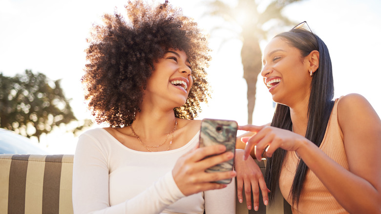 women laughing and sharing drink