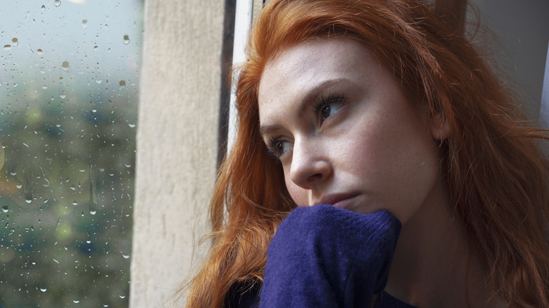 Woman staring out rainy window