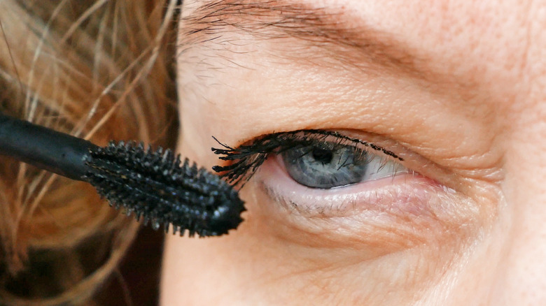 Model with eyelid ptosis applying mascara