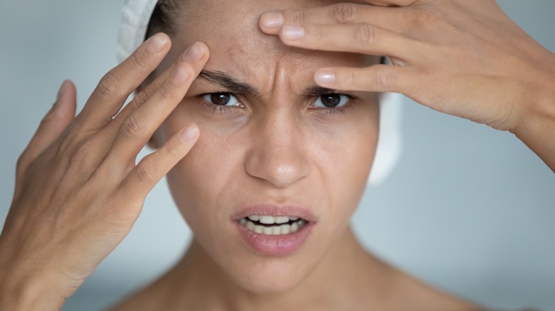 Model examining skin and looking unhappy