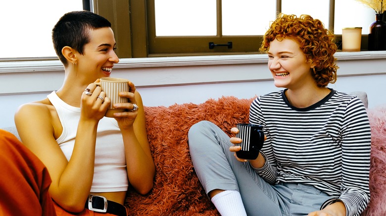 Two women chatting and drinking coffee on sofa