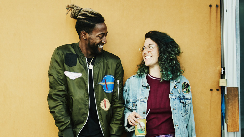 Smiling man and woman leaning against wall together