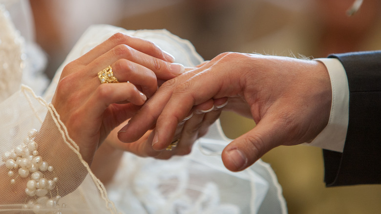 couple hand each other rings