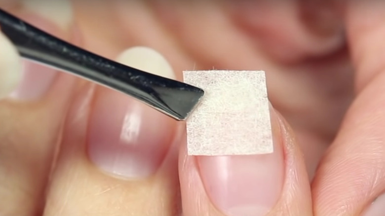 woman applying teabag on nail 