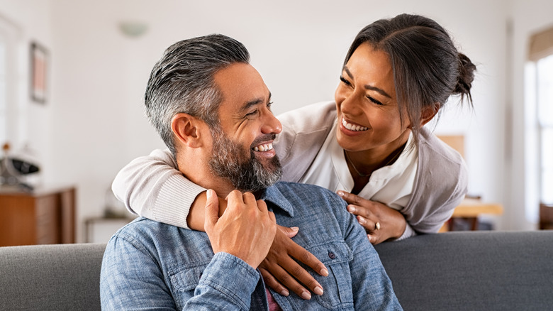 Woman hugging sitting man from behind