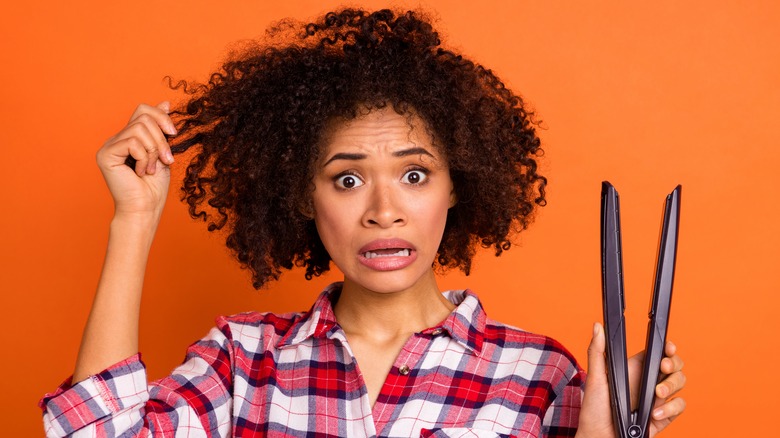 worried woman holding flat iron