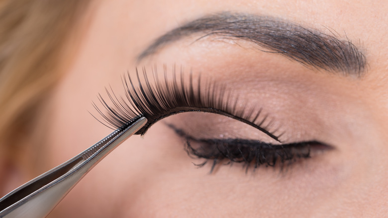 Person putting on fake lashes