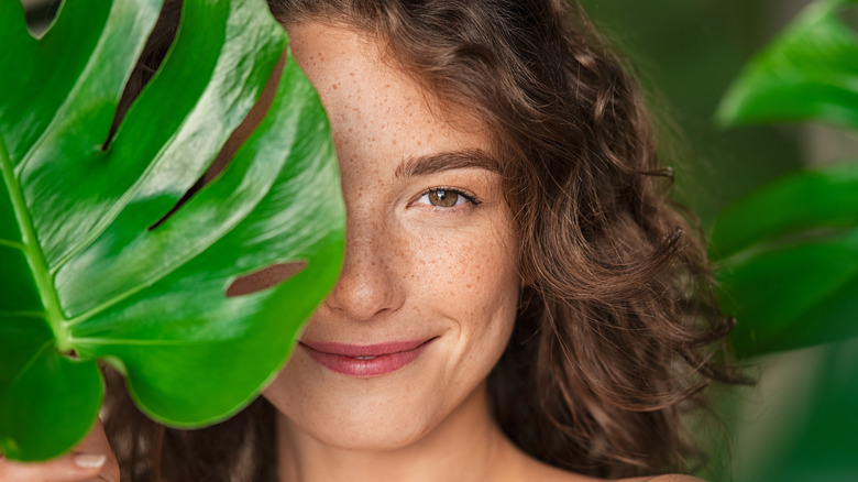 Woman behind monstera leaf