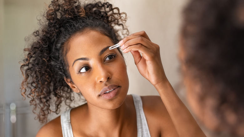 Woman plucking her eyebrows