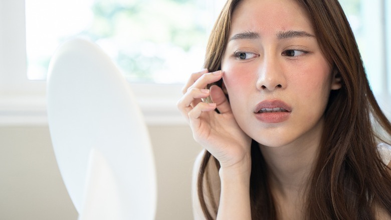 Woman looking at skin in mirror