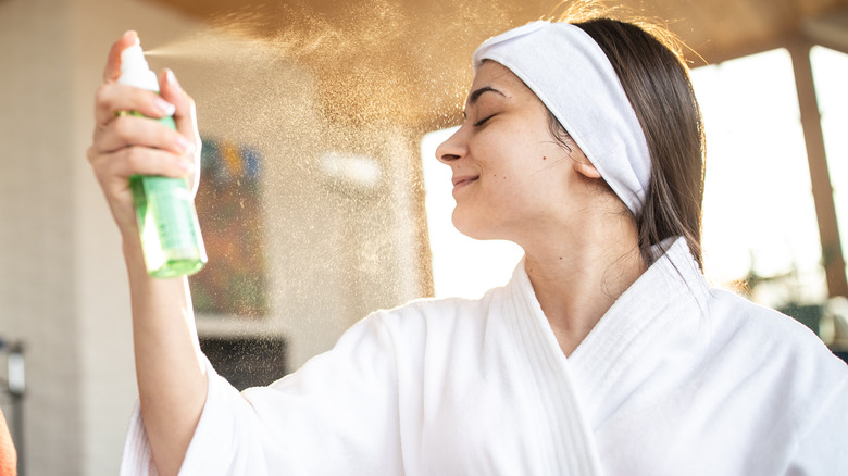 Woman sprays product onto face