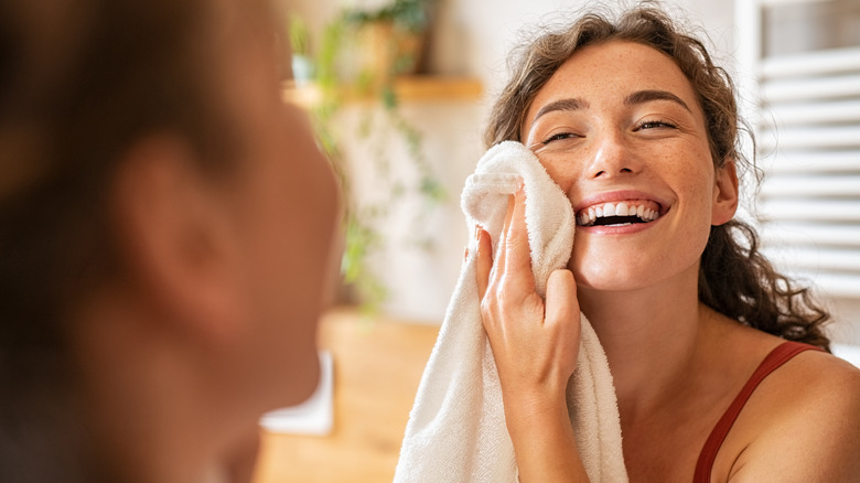 Woman wiping face with towel