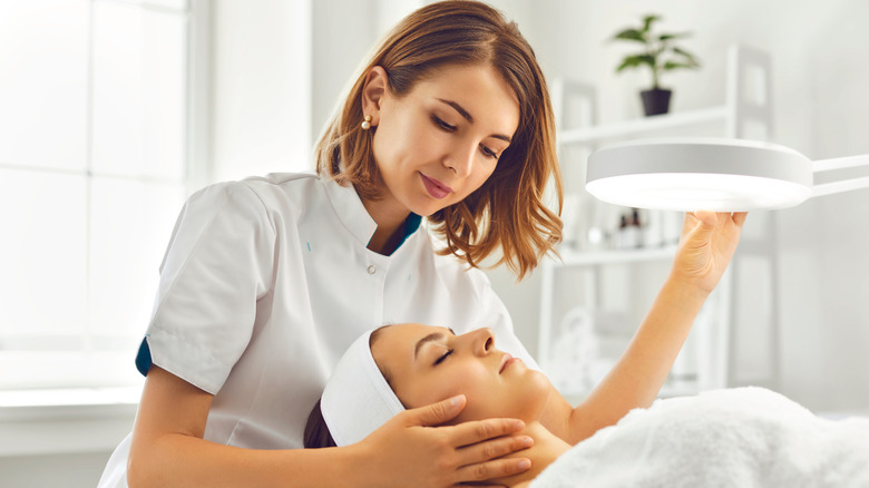 woman examining skin of client