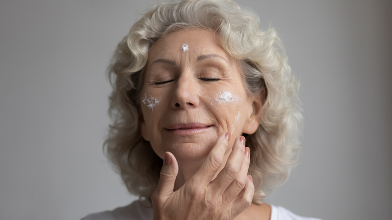 Older woman applying skin cream 