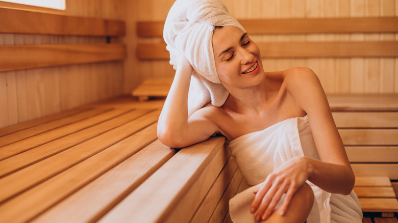 Woman wears towels on body and head in sauna