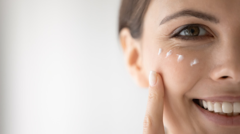 smiling woman applying eye cream