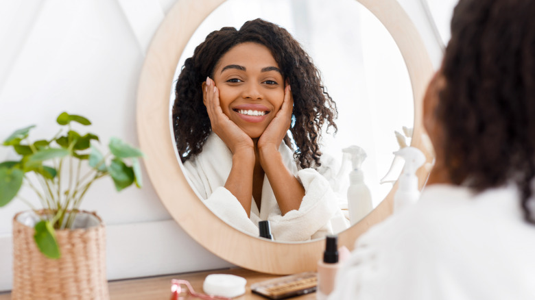 Woman applying makeup in the mirror