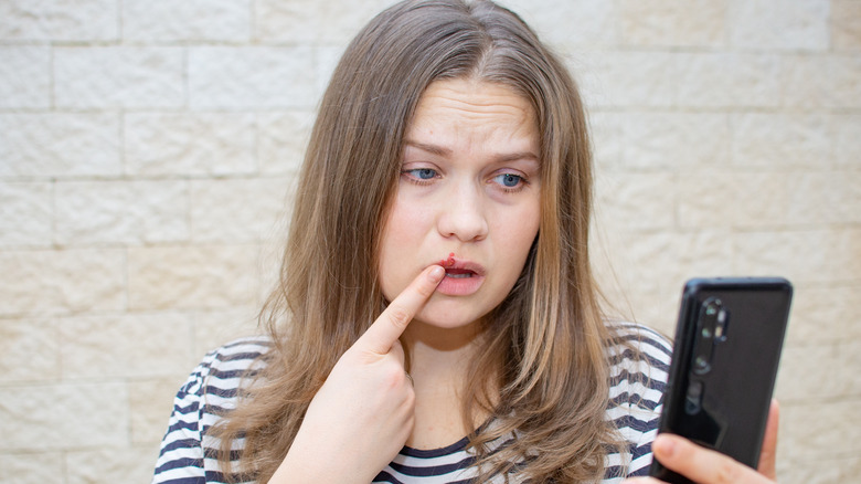 Woman using phone and touching face