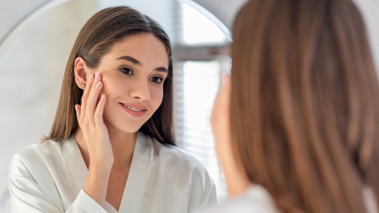 woman checking her skin in the mirror