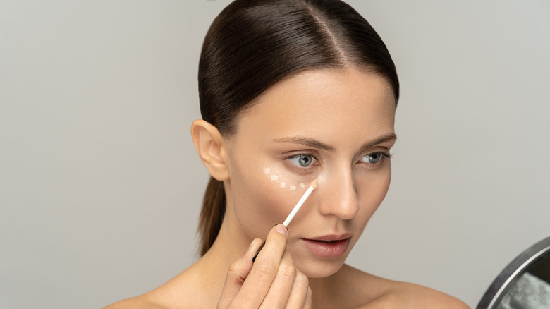 Woman applying concealer to face