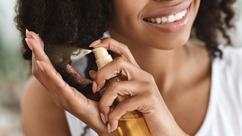 woman spraying product in hair