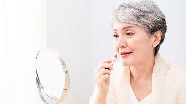 Woman applying pink lipstick