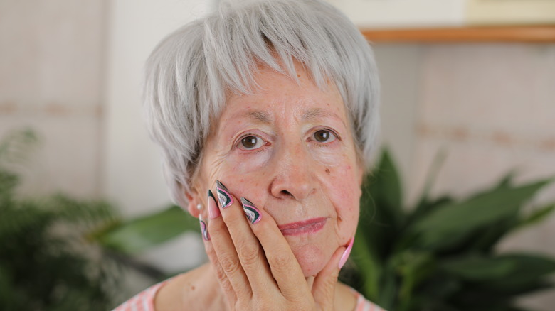 An older woman shows off her colorful stiletto nails.