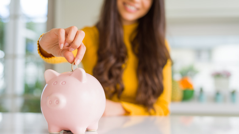 woman putting coin in piggybank