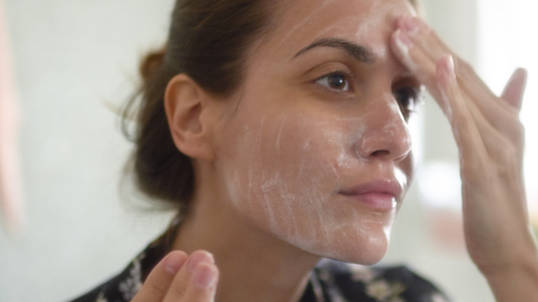 woman applying skincare to face