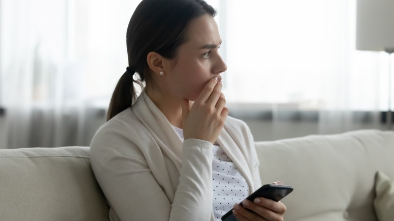 Concerned woman thinking on couch