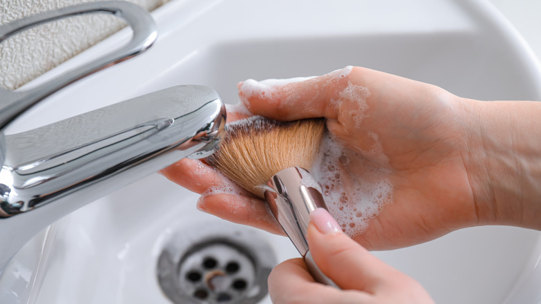 person washing makeup brush