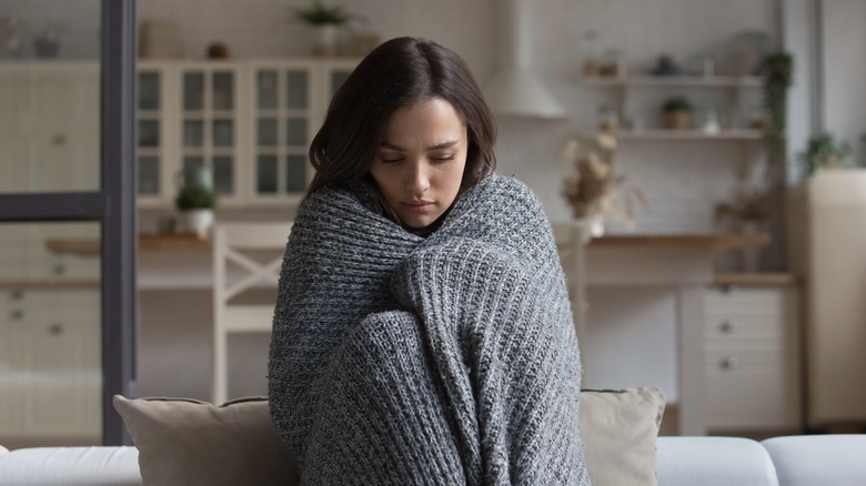 Woman wrapped in blanket looking sad