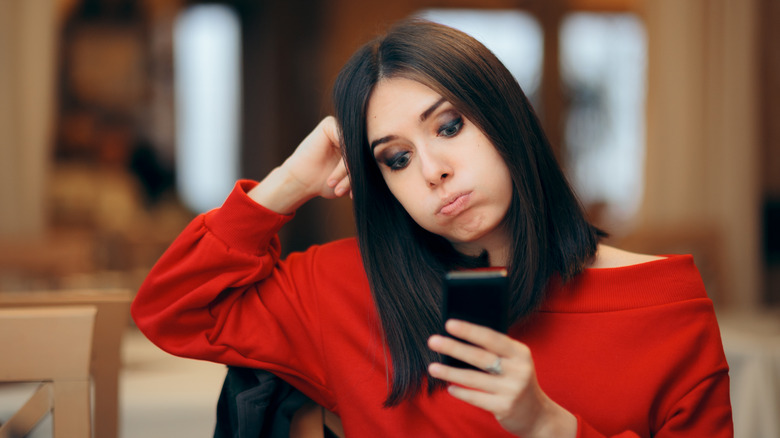 Woman looking anxiously at phone