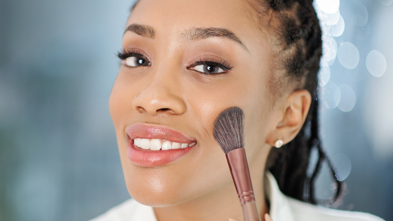 woman applying blush to cheek