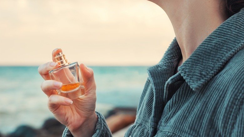 Woman applying perfume by ocean