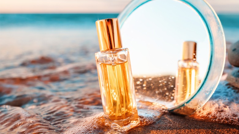 Perfume and mirror on beach