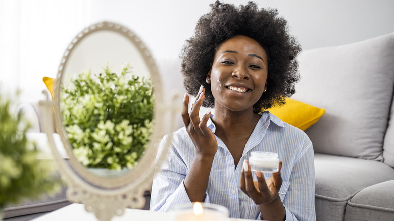 woman applying cream with mirror