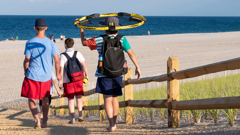 People carrying Spikeball kit to beach